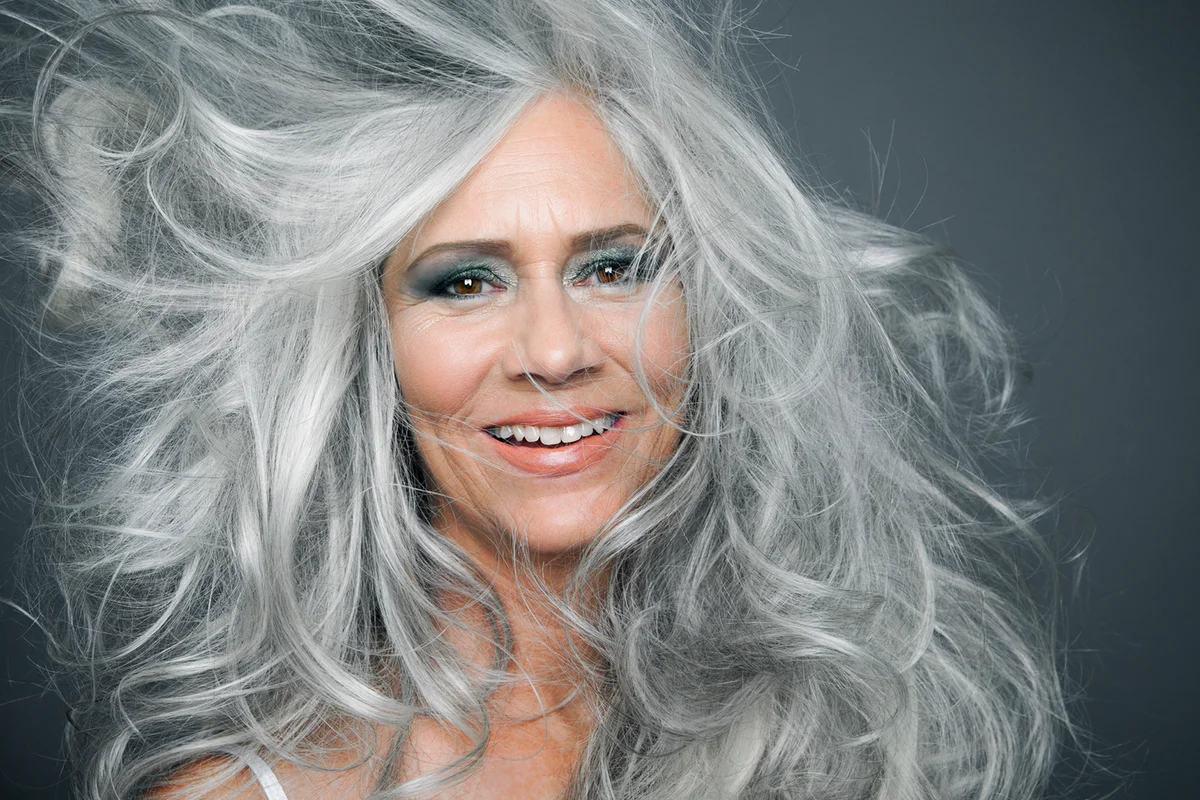 Smiling woman with long, grey hair blowing
