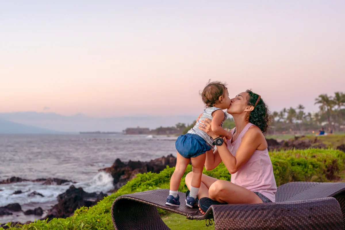 Woman giving toddler daughter a kiss