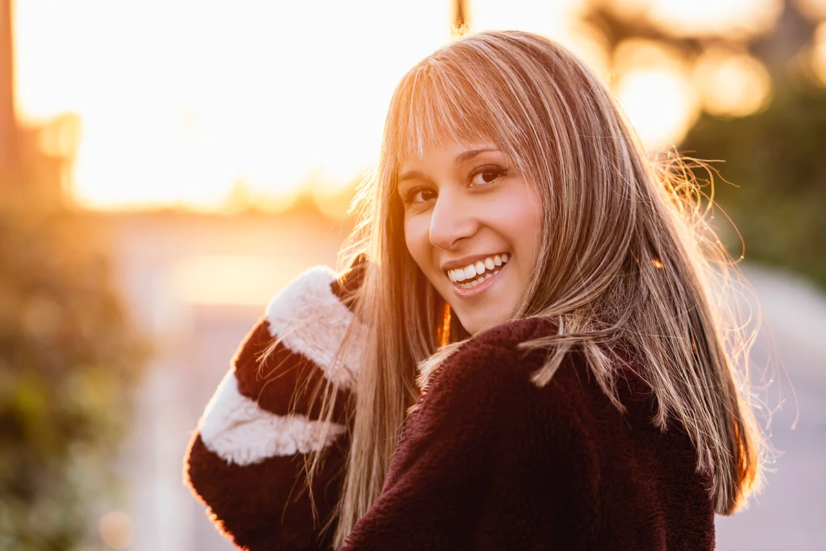 Young woman wearing fur jacket walking on street during sunset