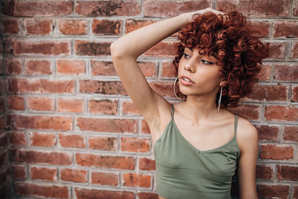 Redhead lady standing against the brick wall