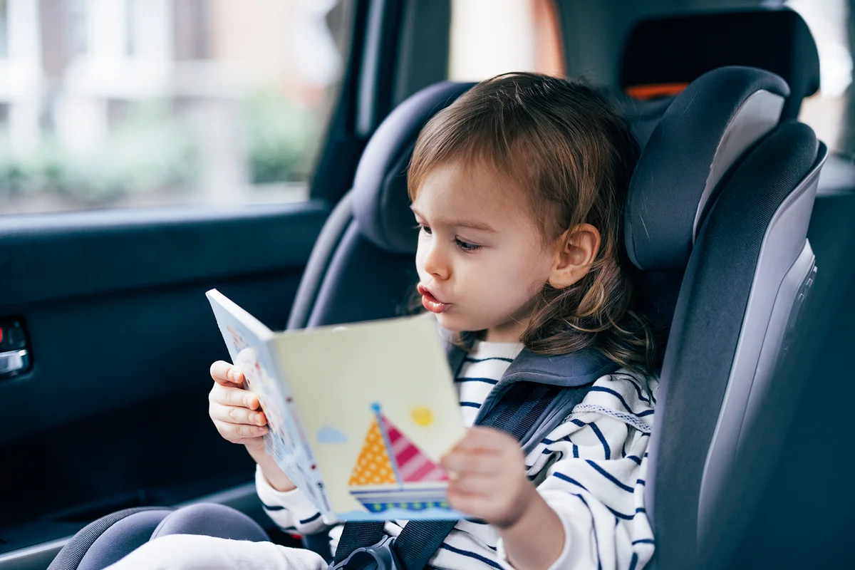 Little Girl Reading a Book While Traveling by Car