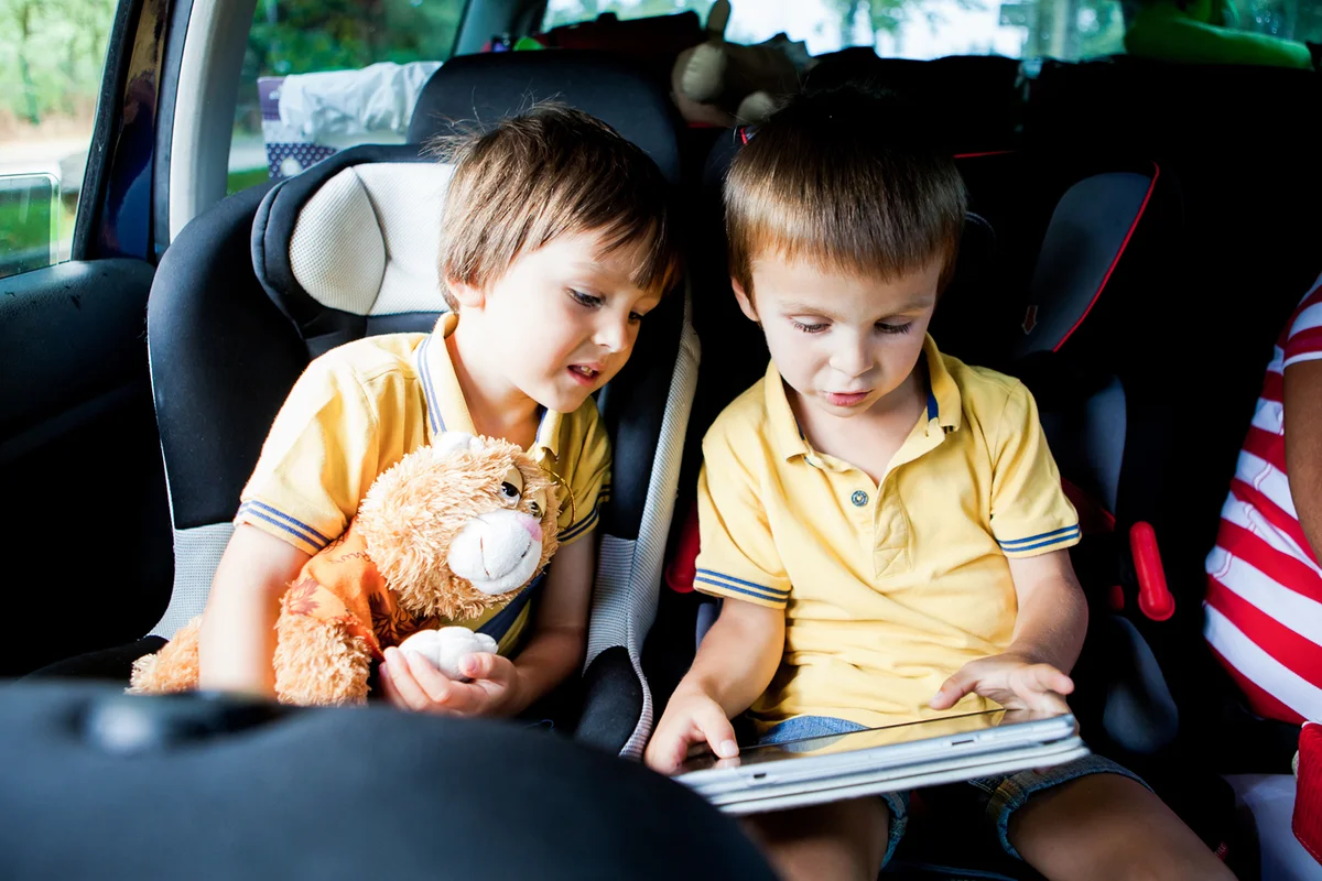 Two cute boys, playing on tablet in the car