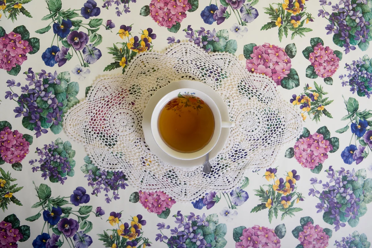 A cup of tea on a floral tablecloth