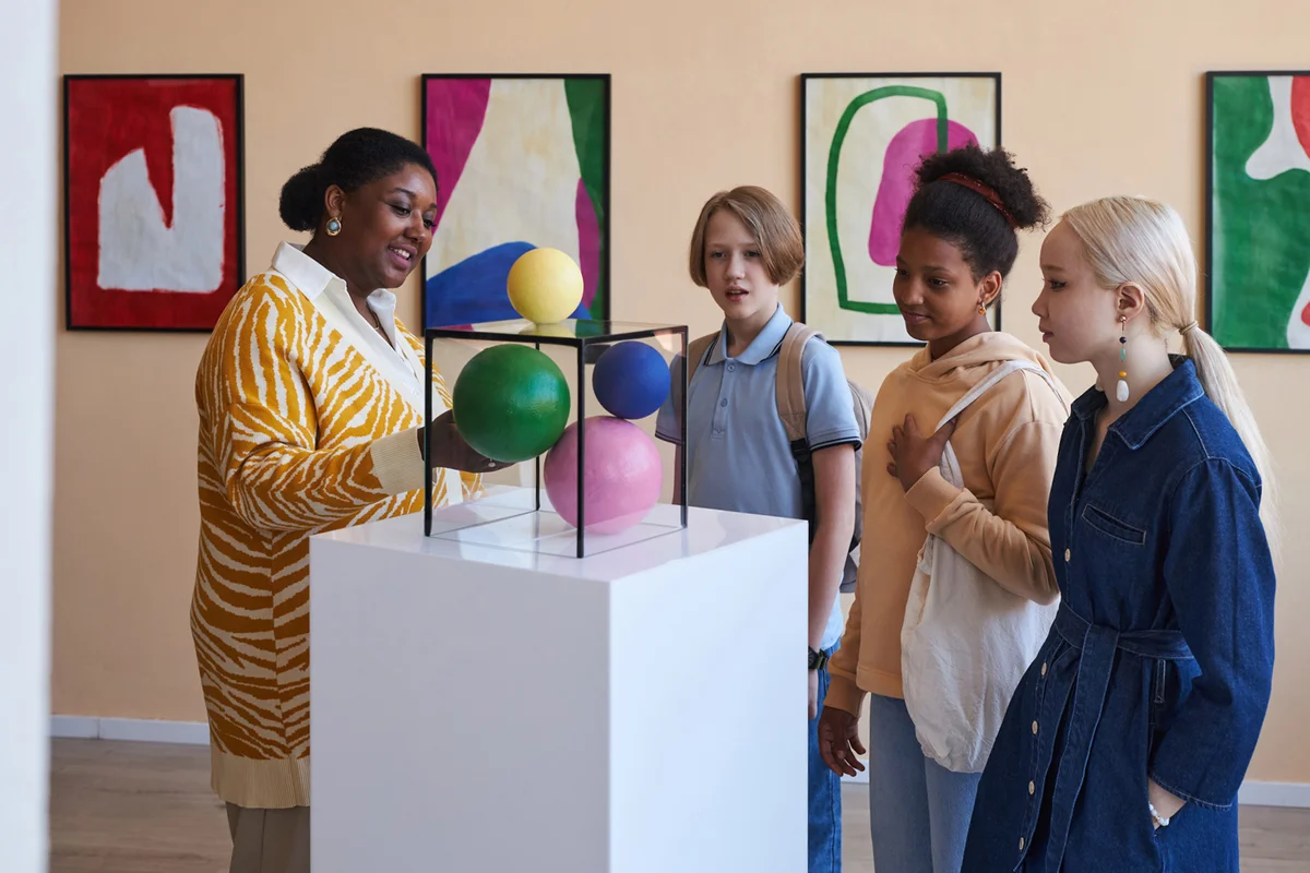 Teenagers listening to teacher or tour guide in modern art gallery