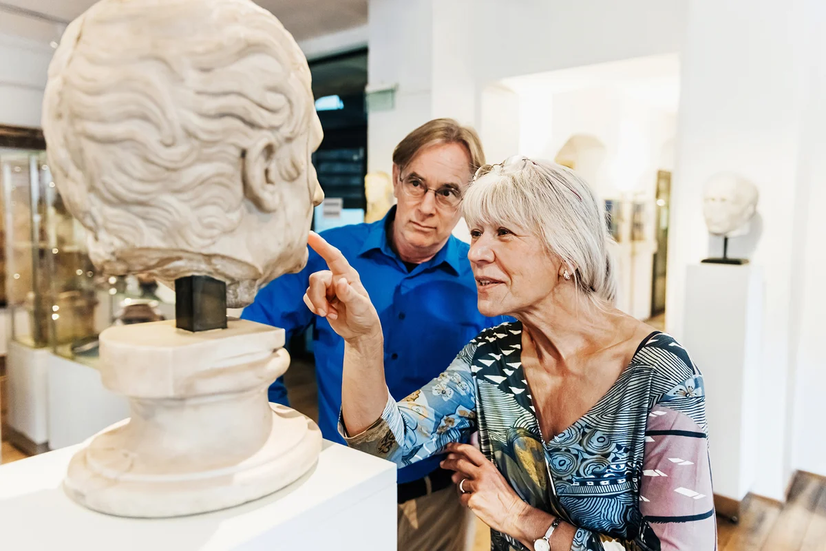 Mature Couple Examining Ancient Bust On Display In Museum