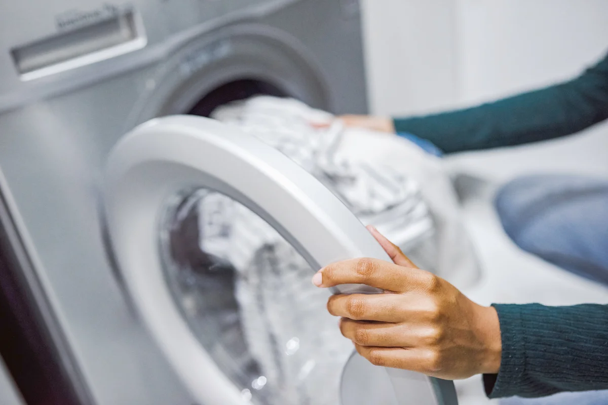 Woman using a washing machine to do laundry