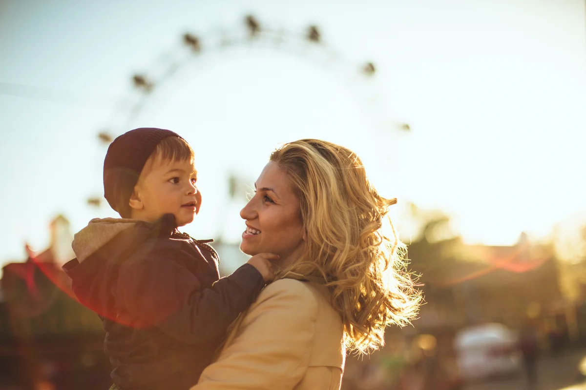 Mother and son enjoy on a sunny day in the amusement park
