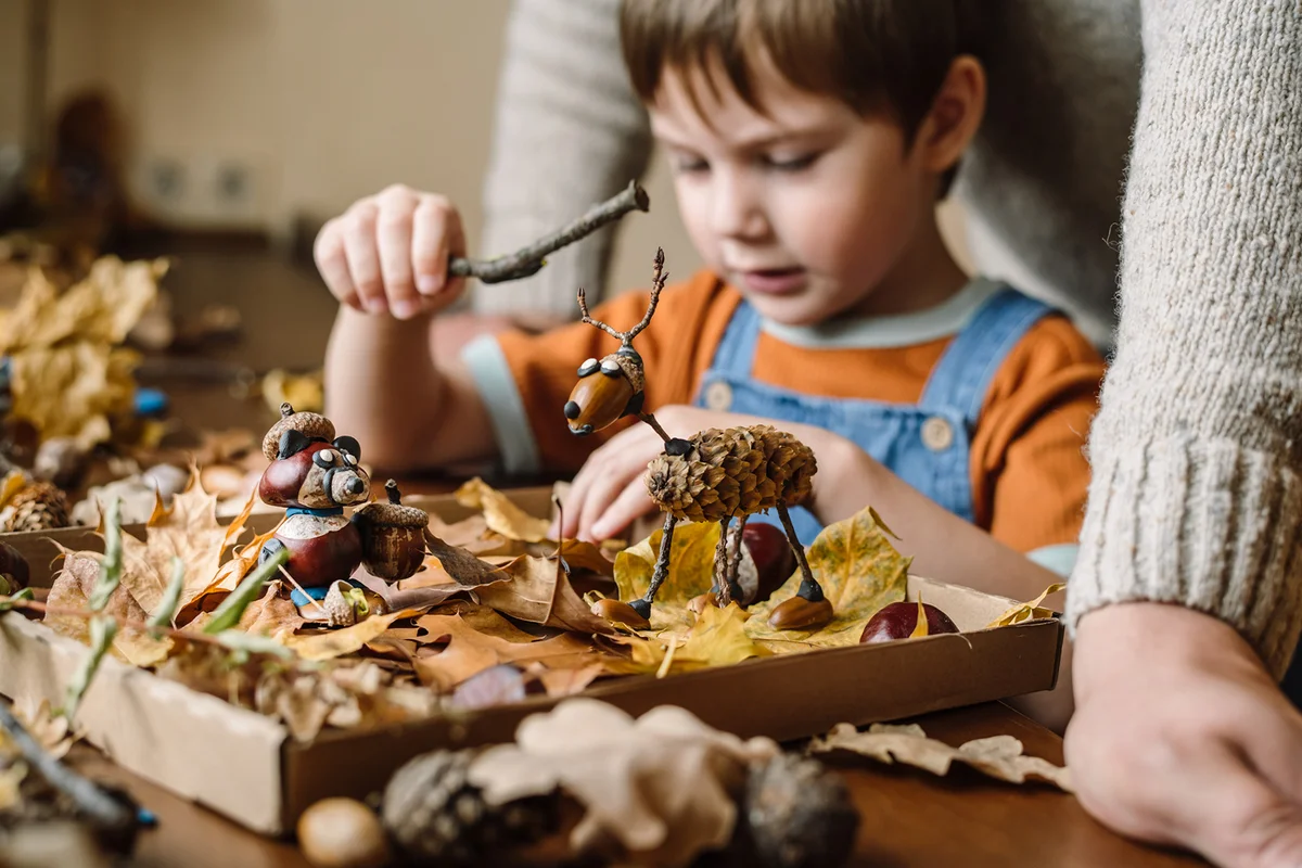 Little boy and his father making handcrafts at home in autumn