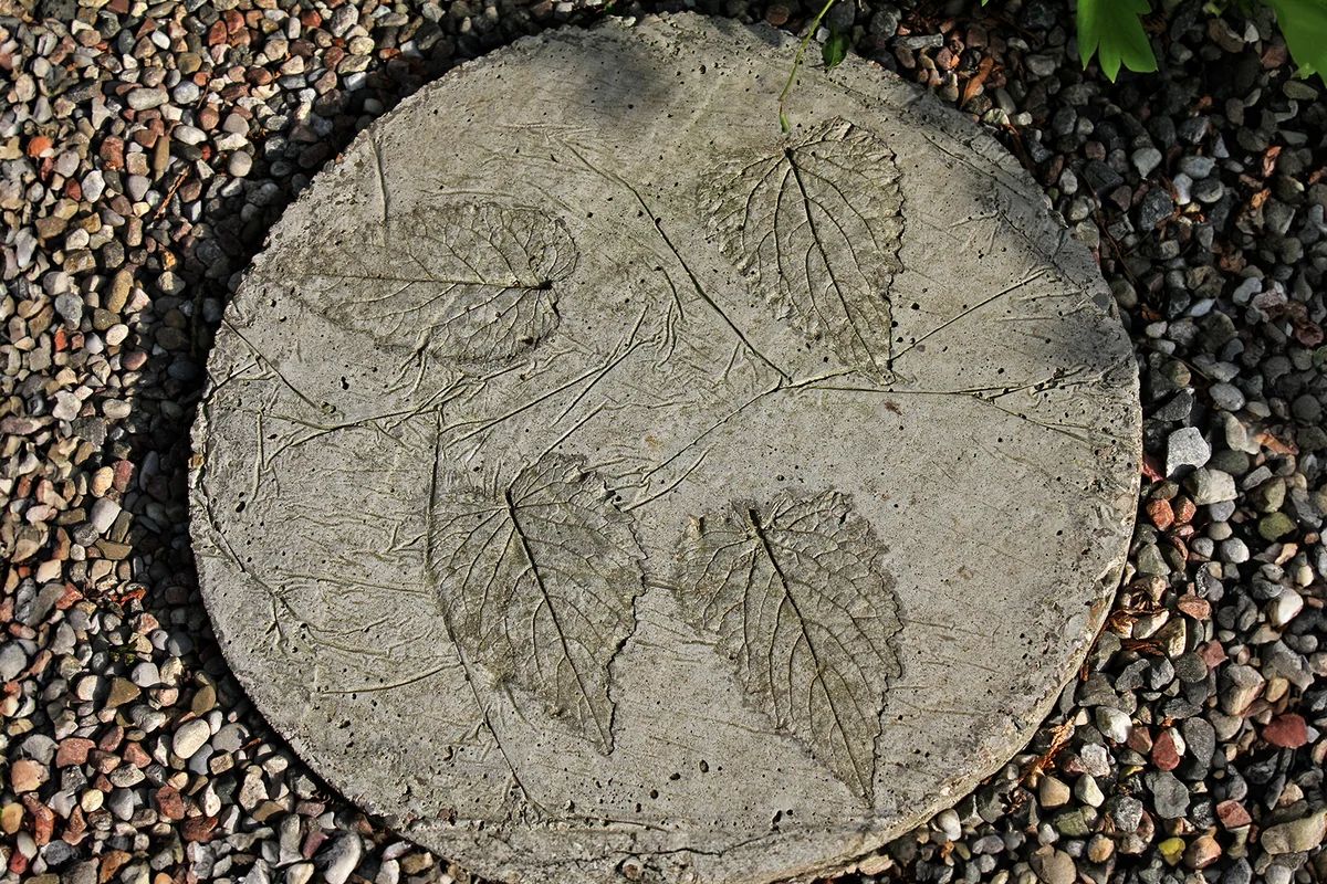 A circular cast of concrete with leaf imprints used as garden decoration