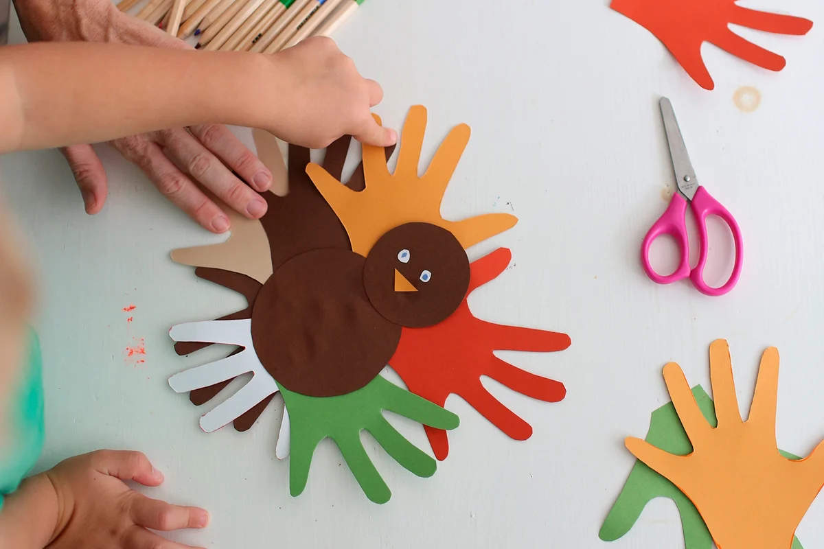 Students and teacher making Thanksgiving turkey crafts in classroom