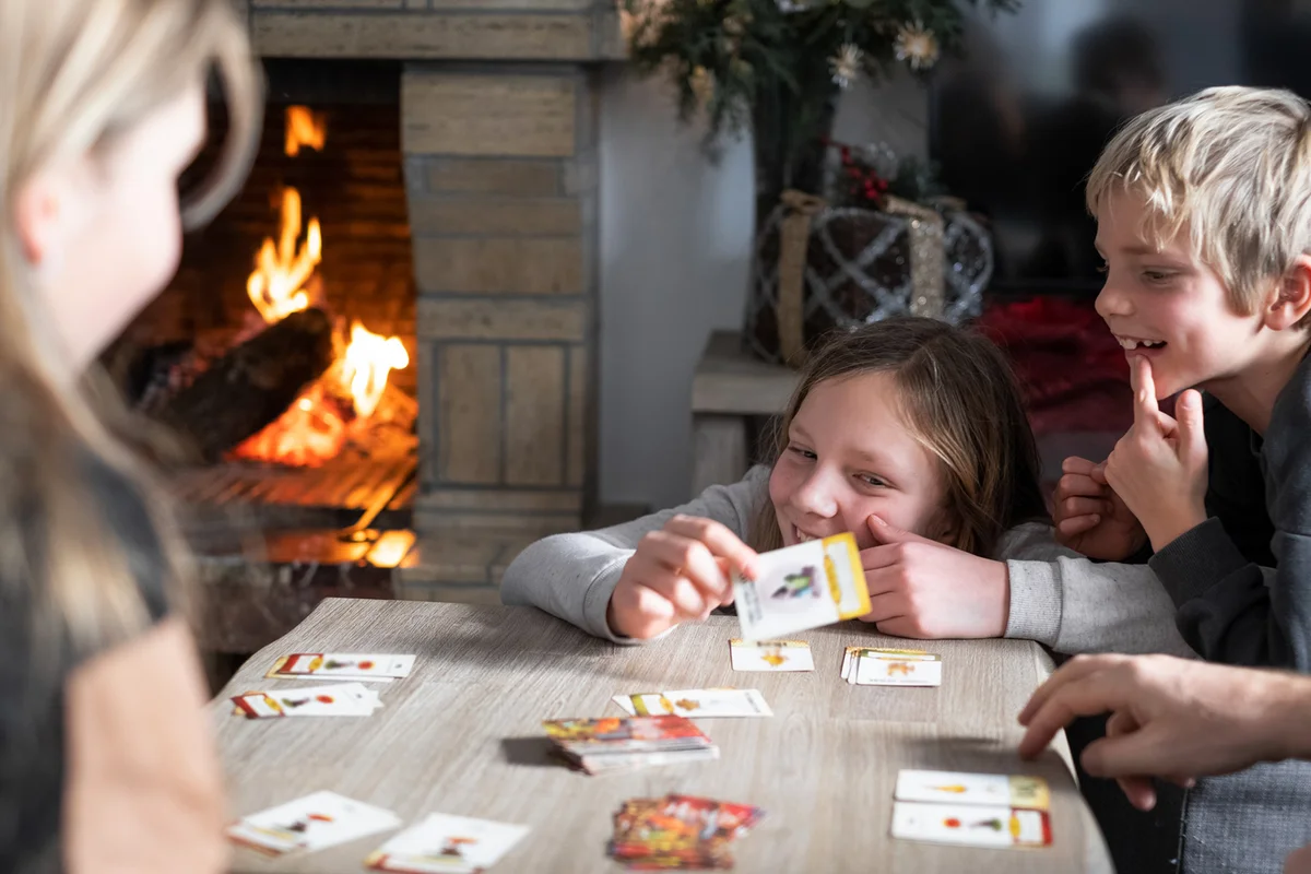 Siblings playing cards with the family at home