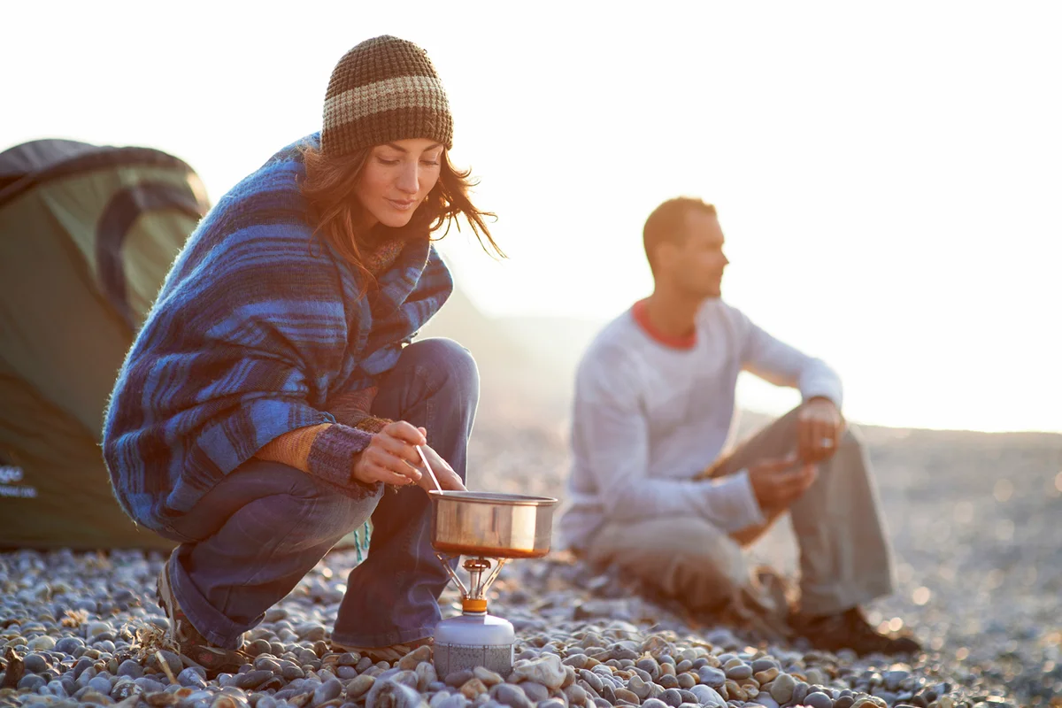 Woman cooking outside tent on beach