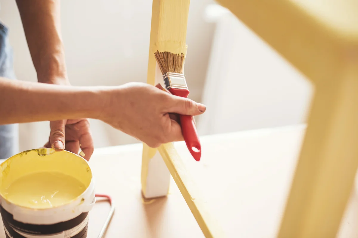 Person painting yellow furniture