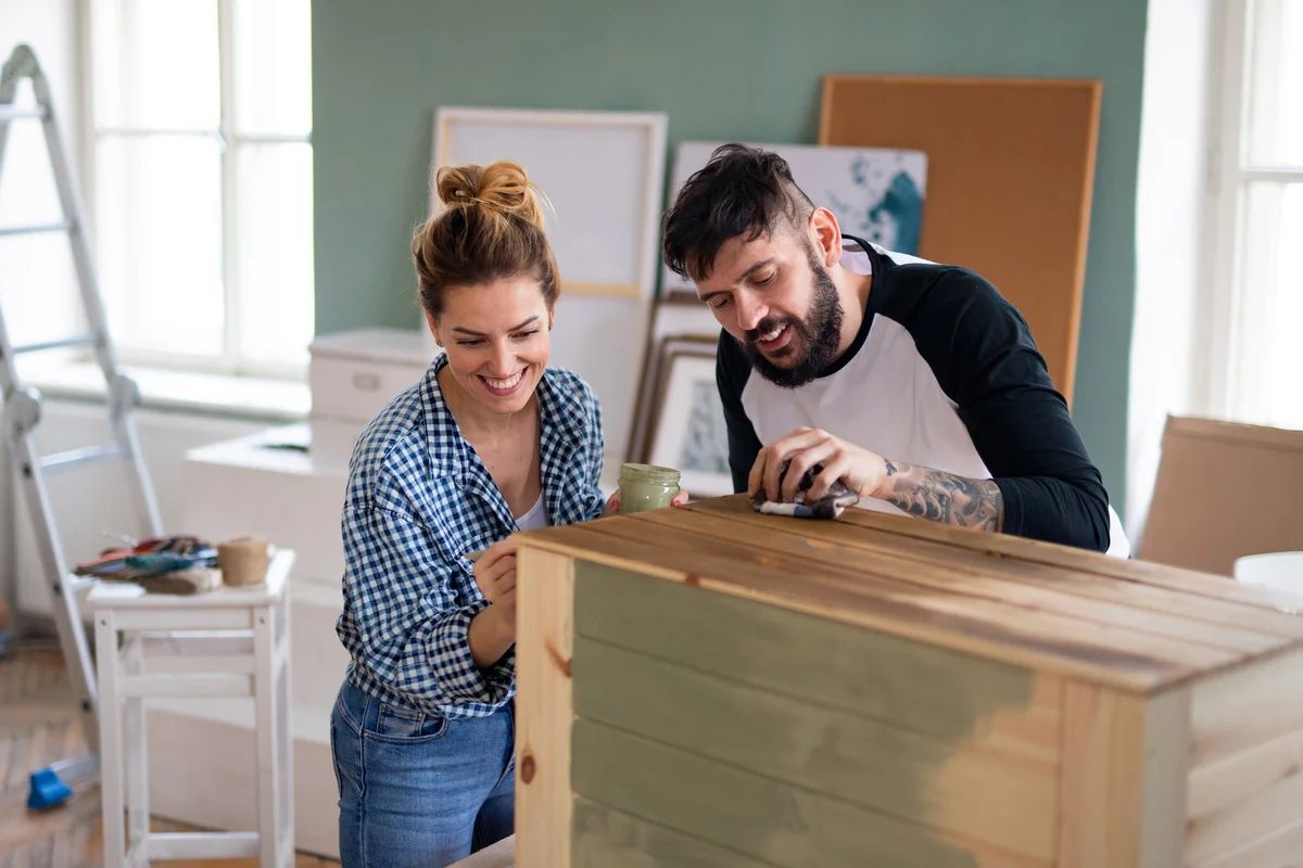 Happy mid adults couple painting furniture indoors at home