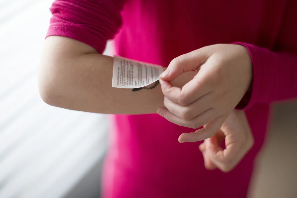 Child applying temporary tattoo to arm