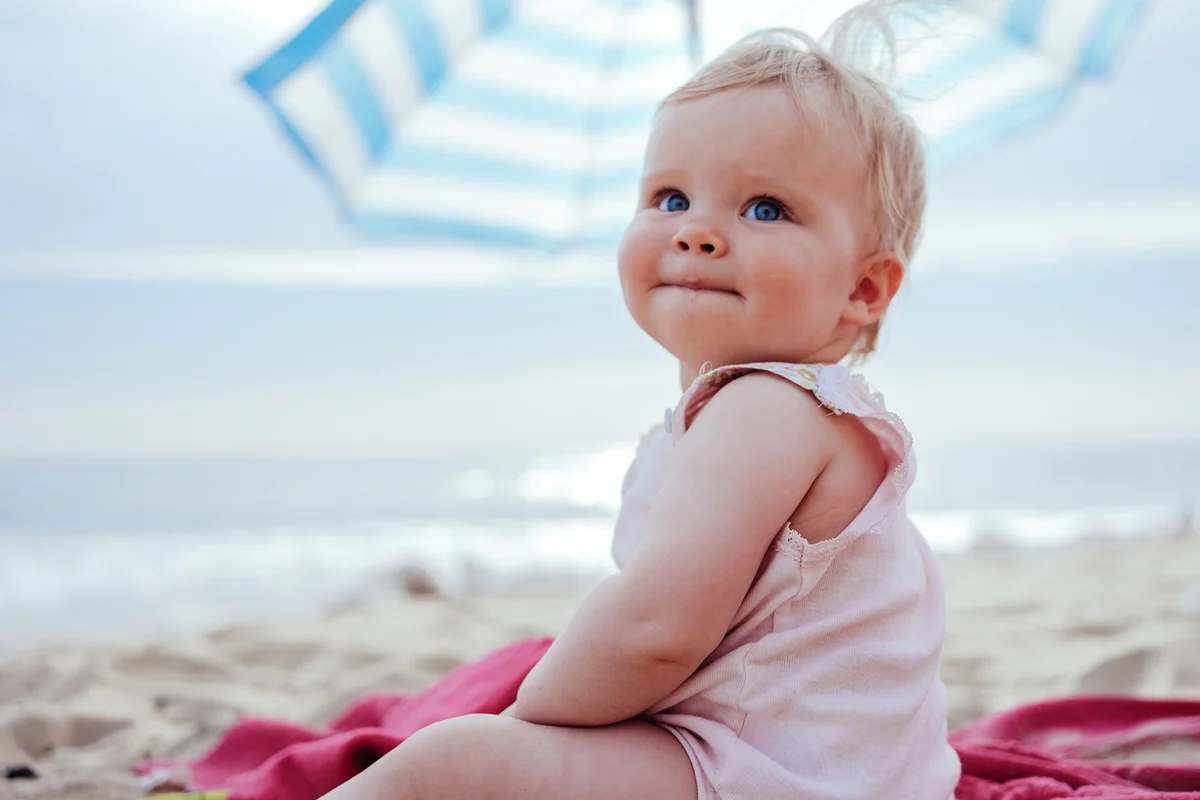 Happy little blondhaired toddler girl sitting at the beach