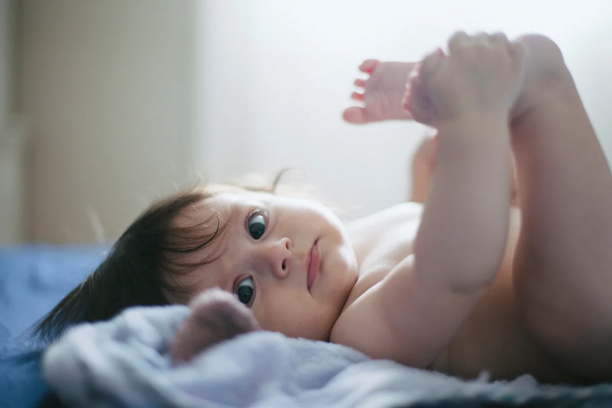 Portrait of babygirl holding her feet in her hands