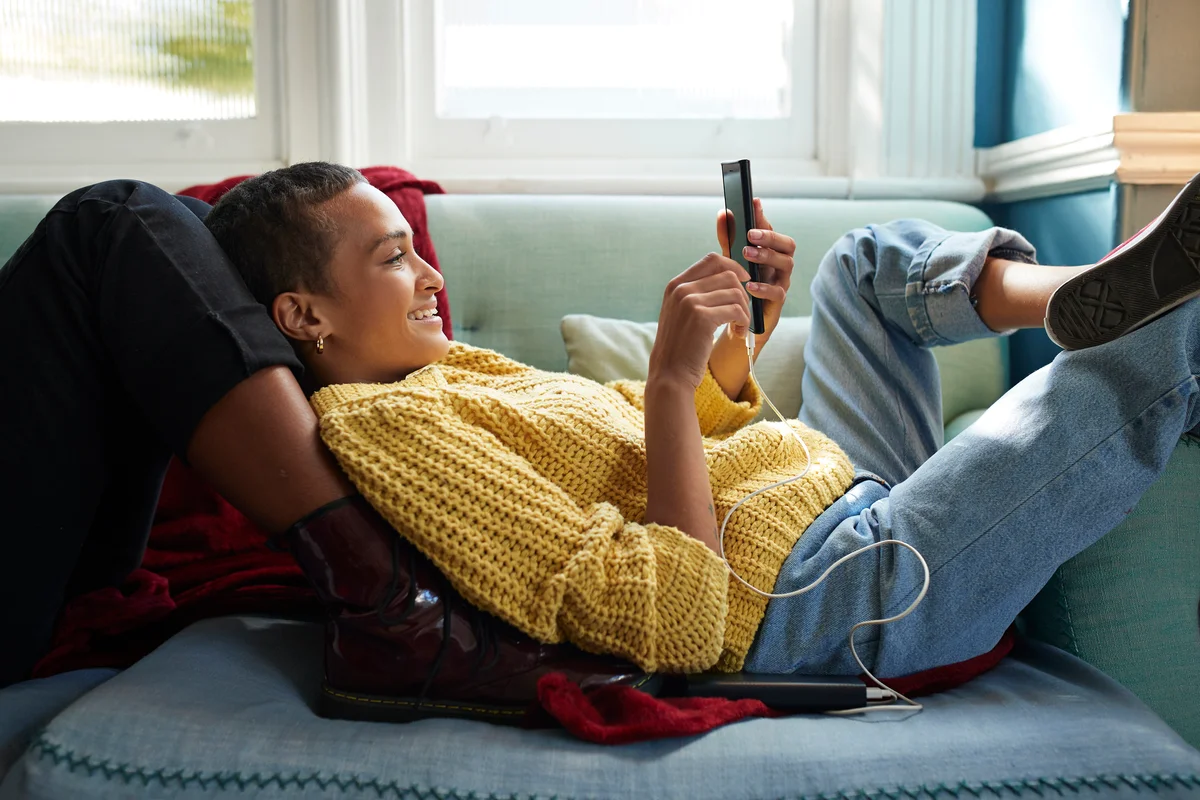Woman messaging on phone while leaning on friend