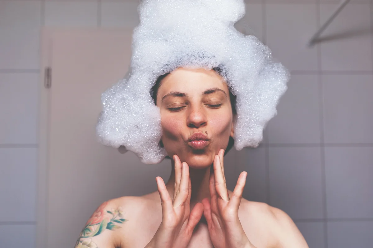 woman in shower with bubbles on hair