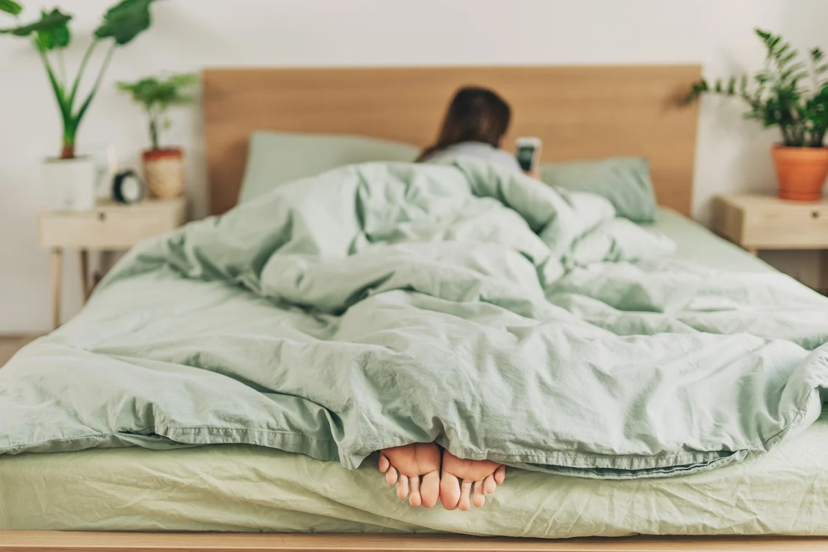 woman in bed with feet under covers