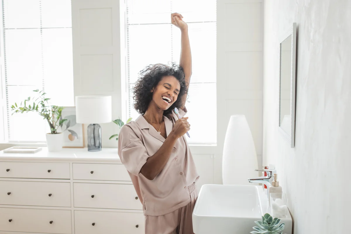 Smiling woman brushing healthy teeth in bathroom