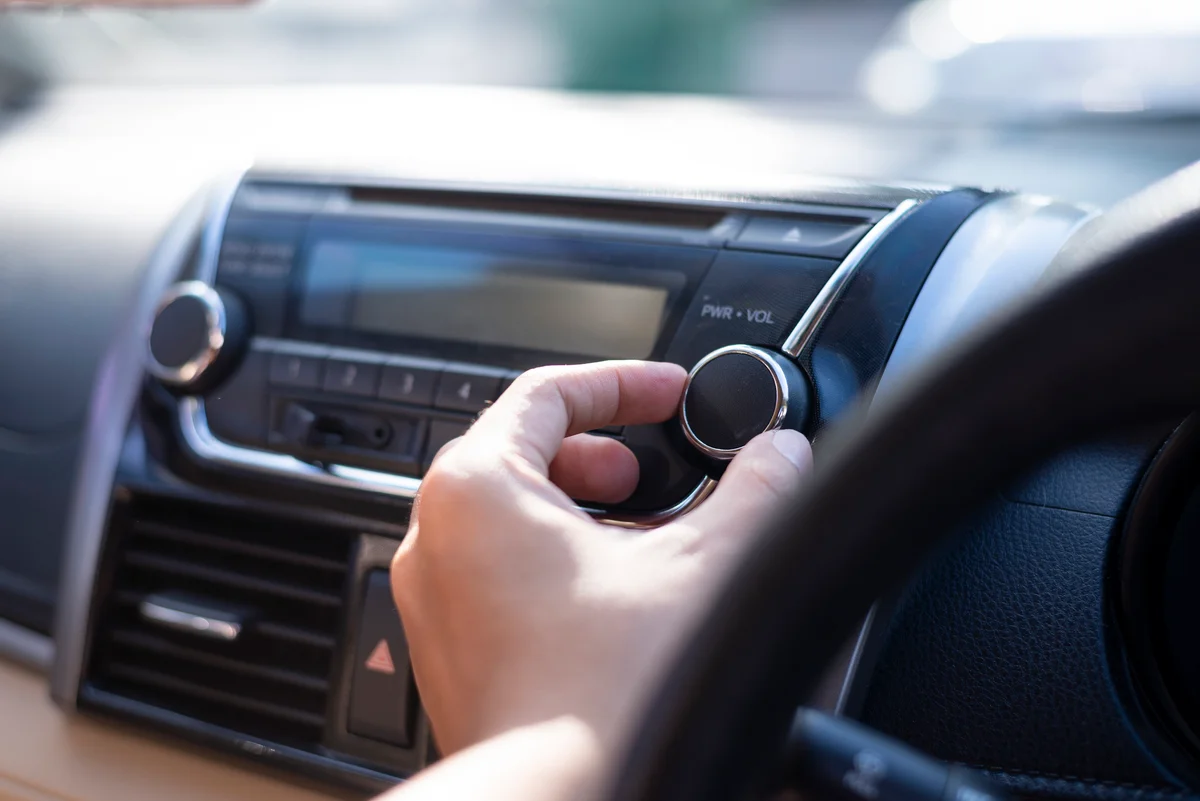 Person turning down volume while driving