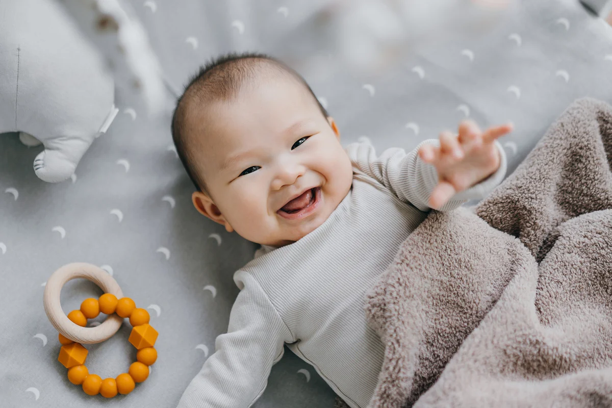 baby girl smiling sweetly while lying on the crib