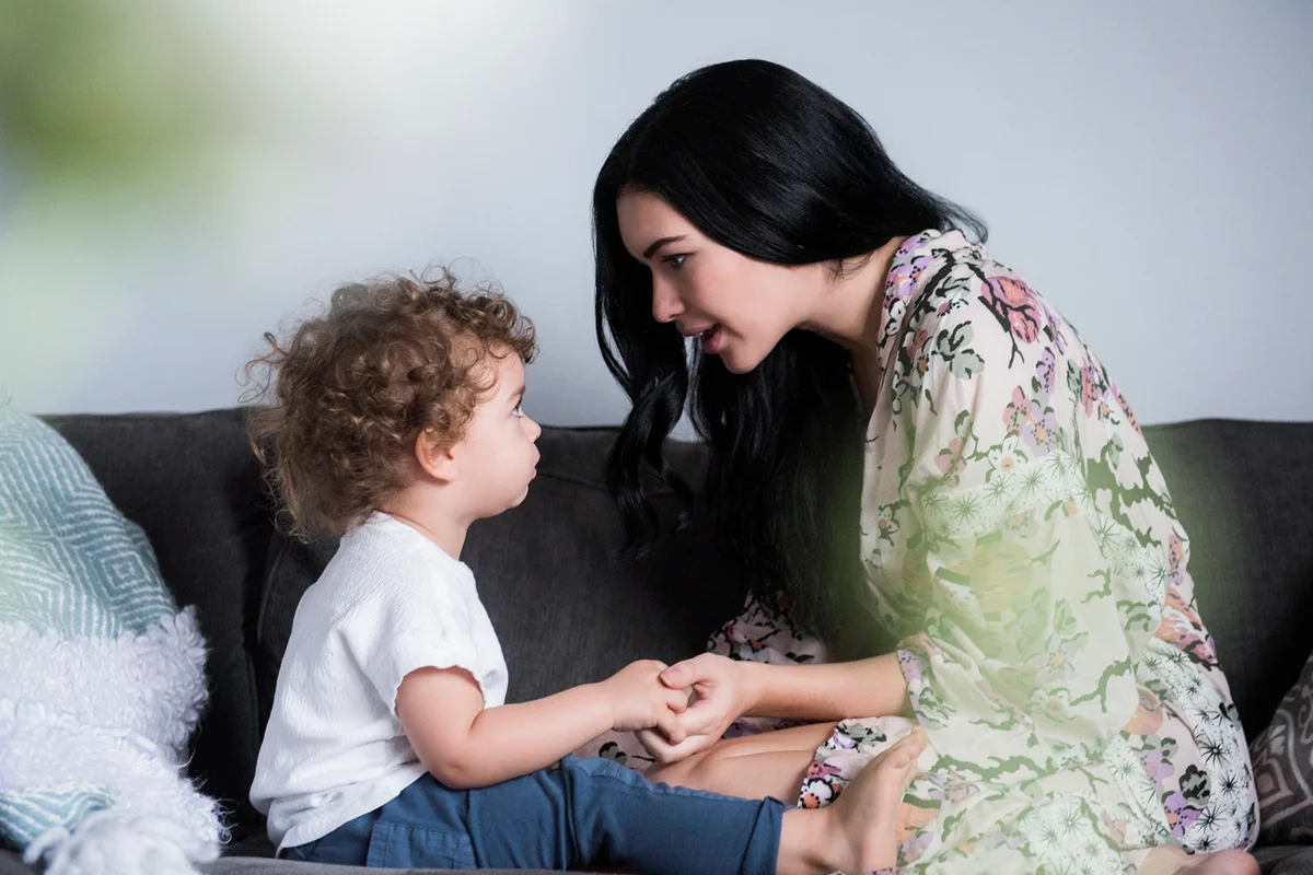 mother sitting on sofa holding hands and talking with son