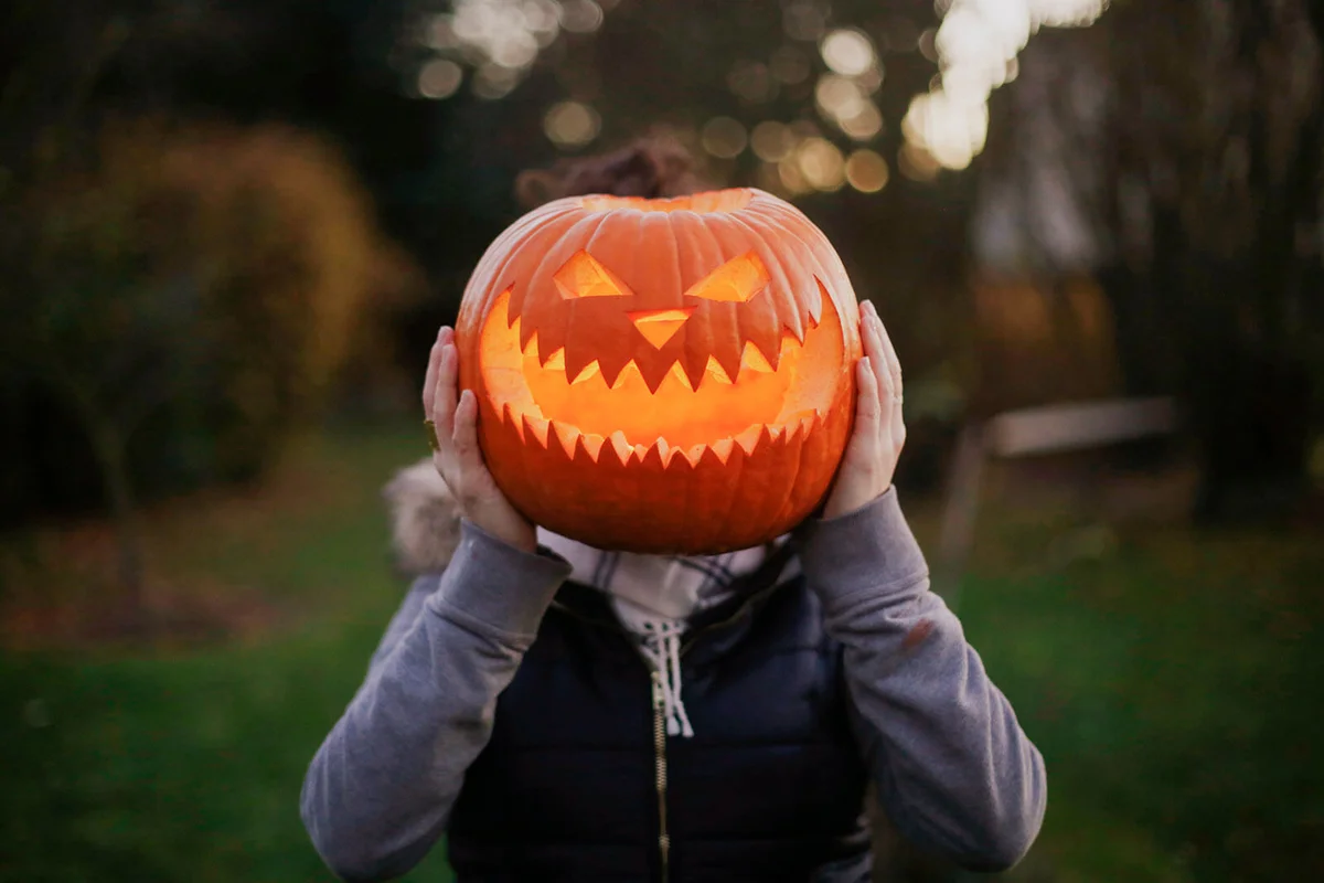 A girl with Halloween pumpkin in front of her head