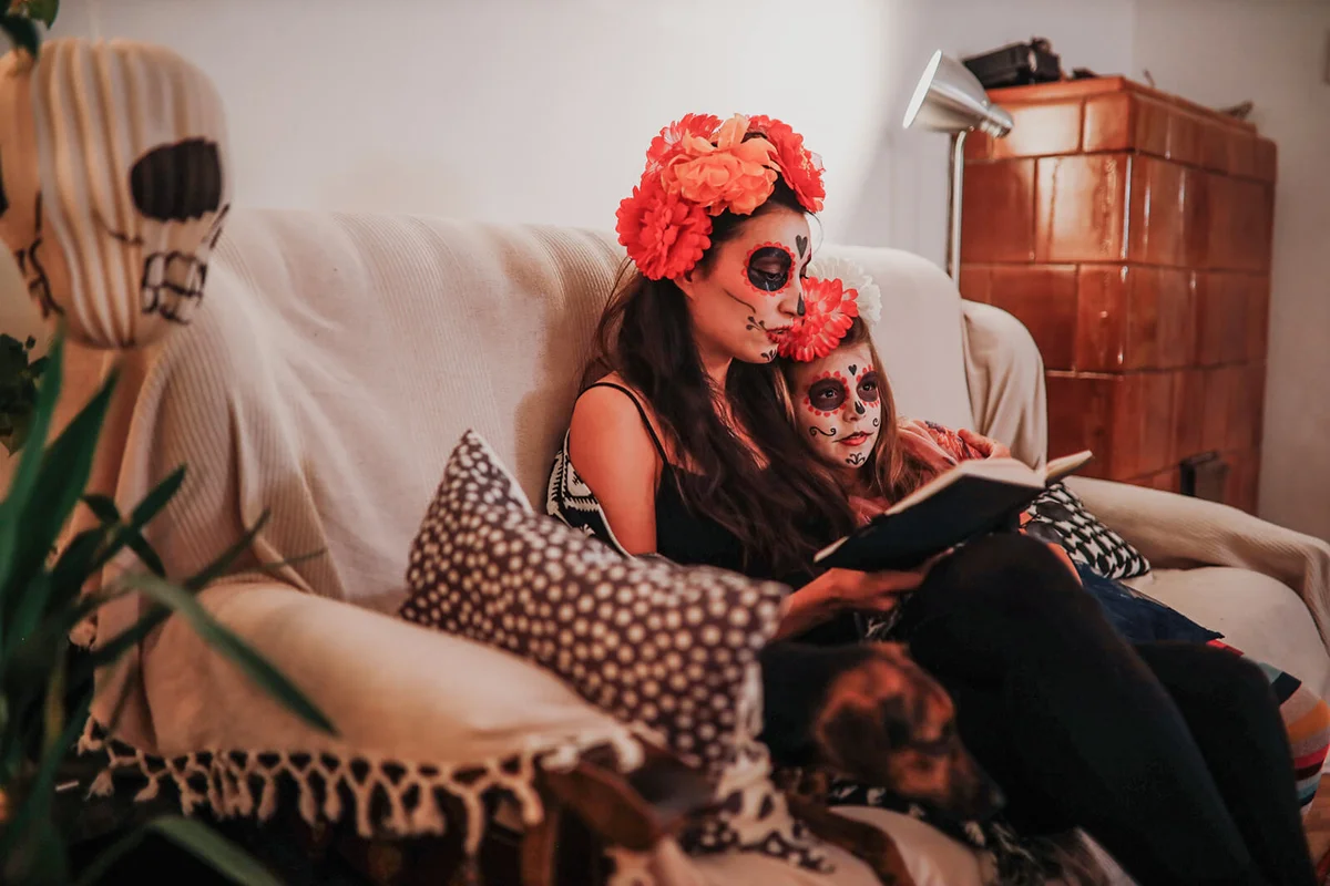 Mom reading spooky tales to her daughter on the Day of the dead
