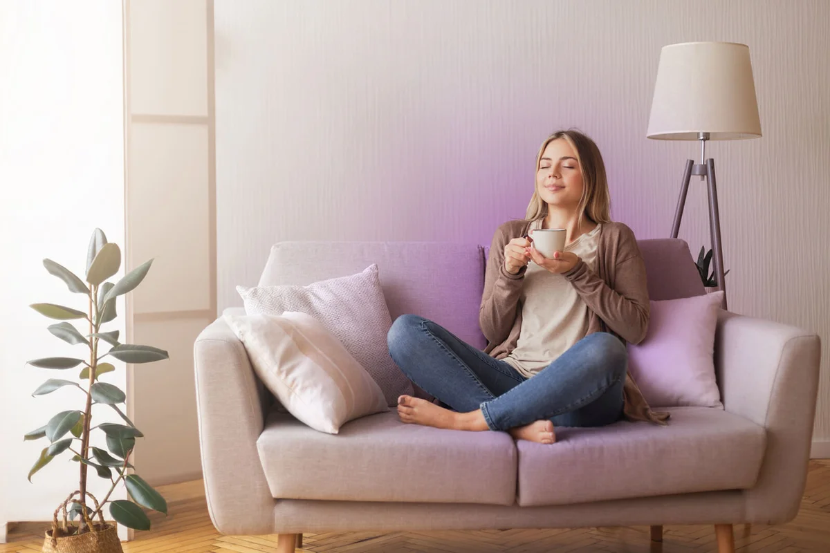 Young coffee lover sniffing hot drink at cozy home interior