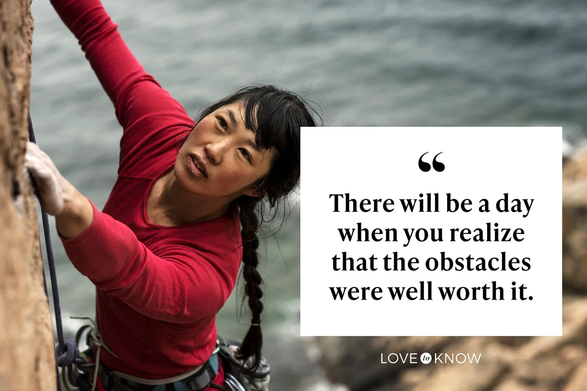 Woman climbing up cliff with ocean in background