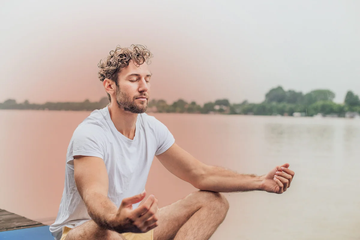 Young man doing yoga outdoors with orange aura
