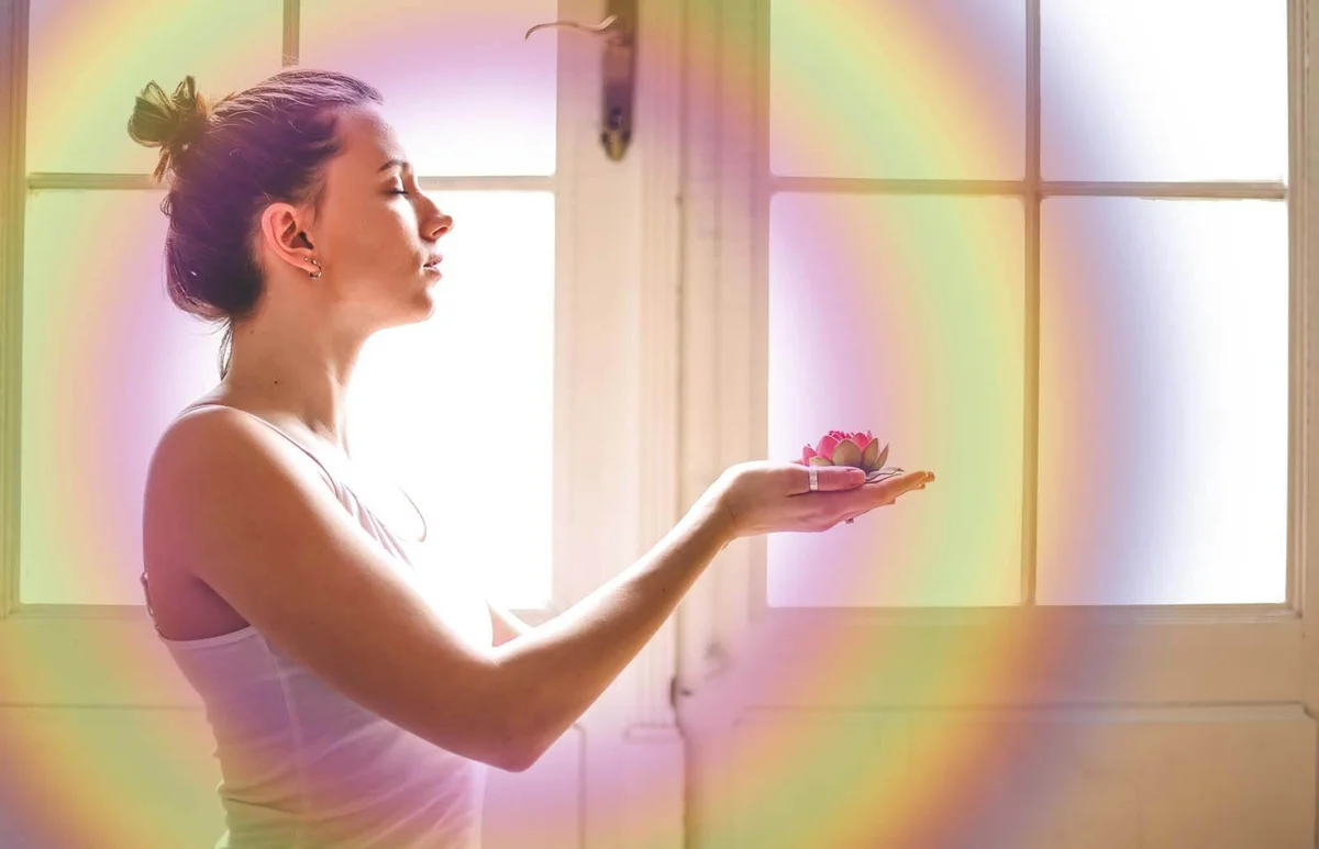 Woman in white clothes in front of the white door holding a lotus flower