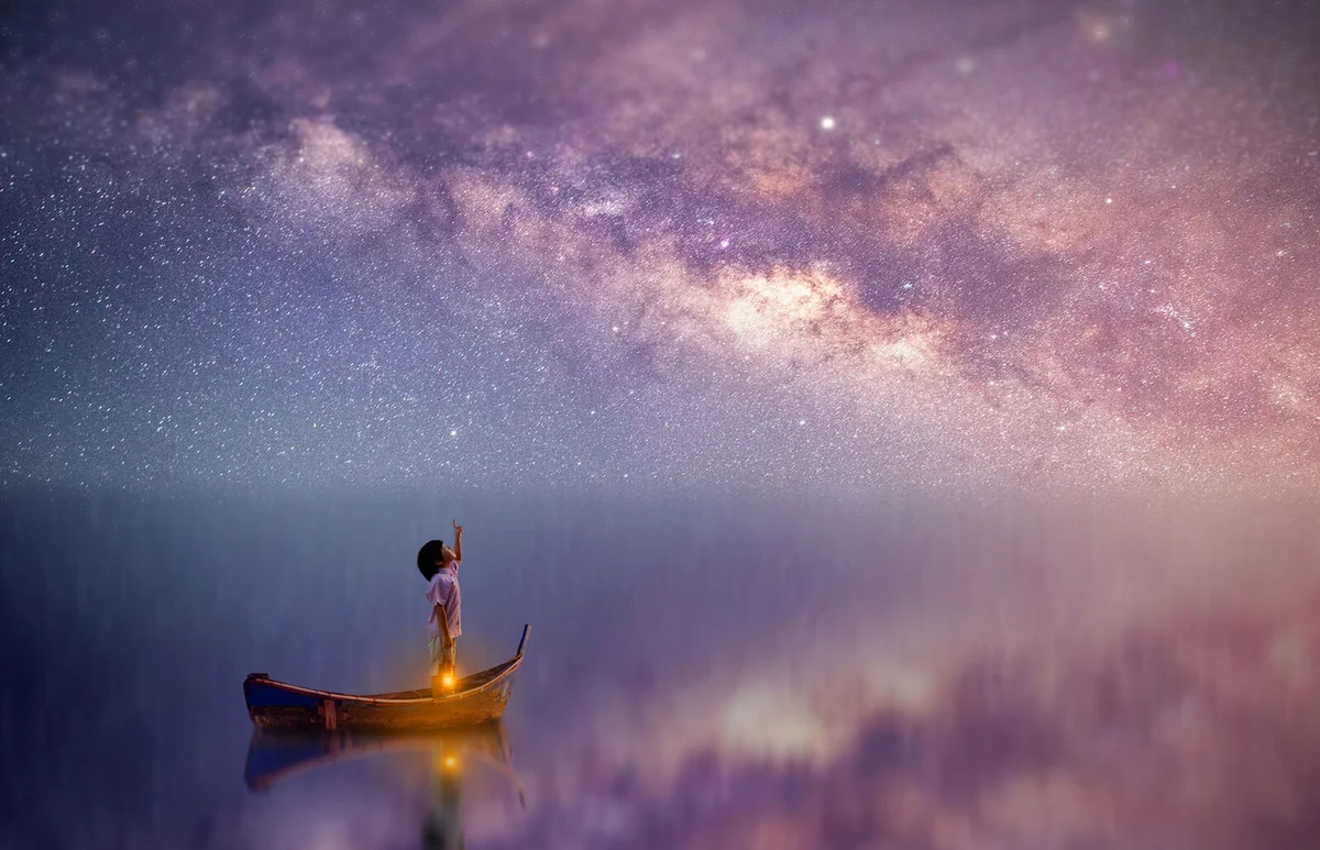 Boy looking at the stars in the middle of the ocean