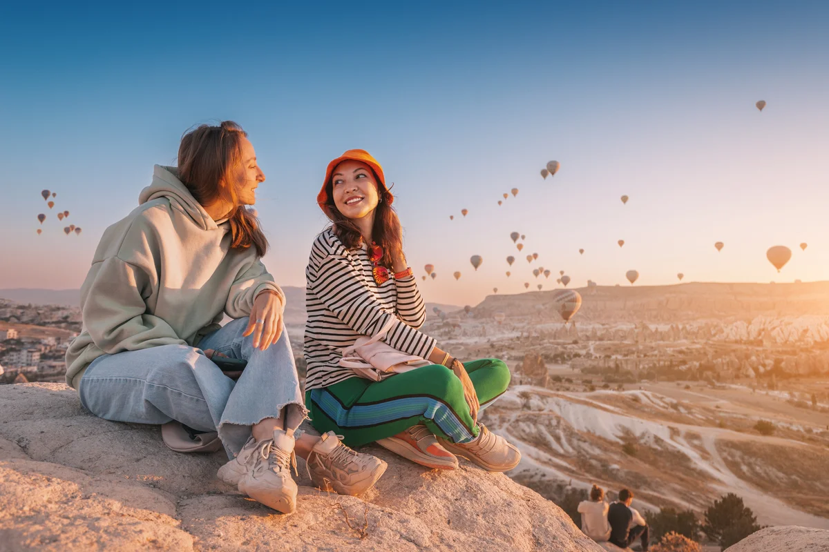 Girl friends sitting on a clifftop viewpoint in Cappadocia