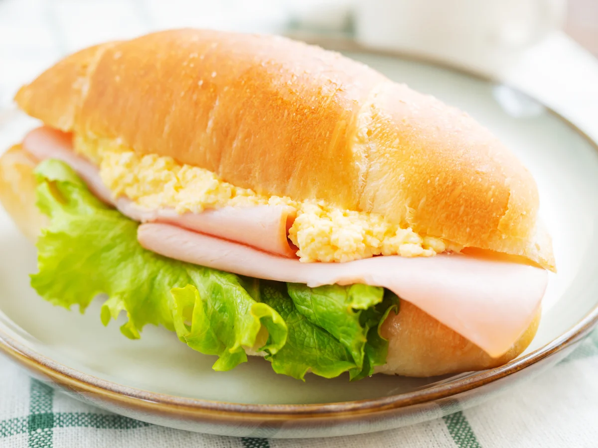 Sandwich with ham,scrambled eggs and lettuce on plate