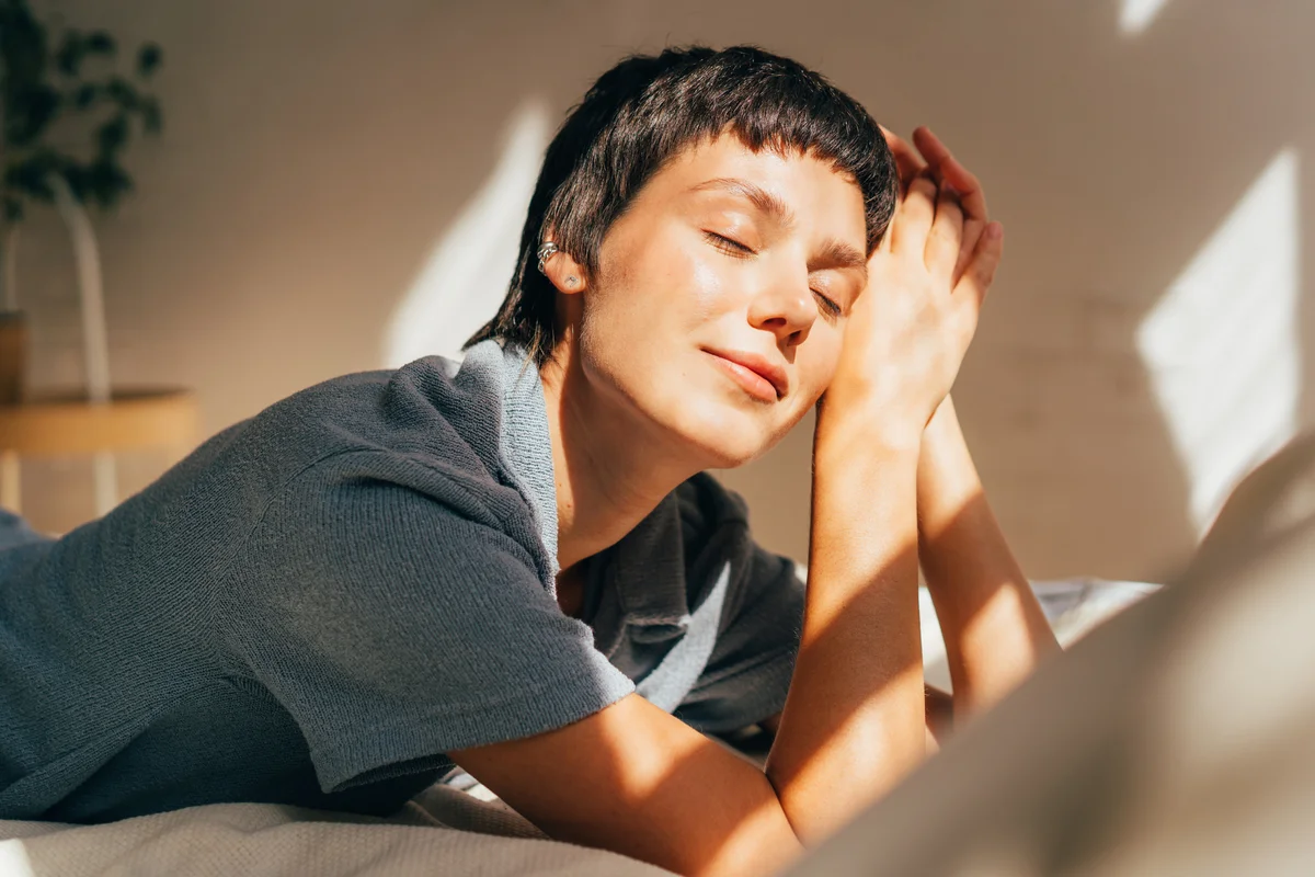woman sunbathing inside home on bed