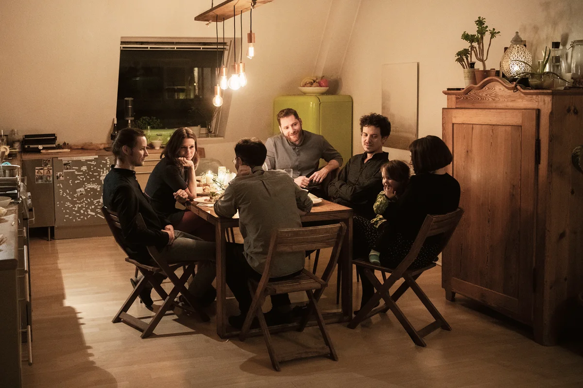 Male and female friends talking at dining table in kitchen
