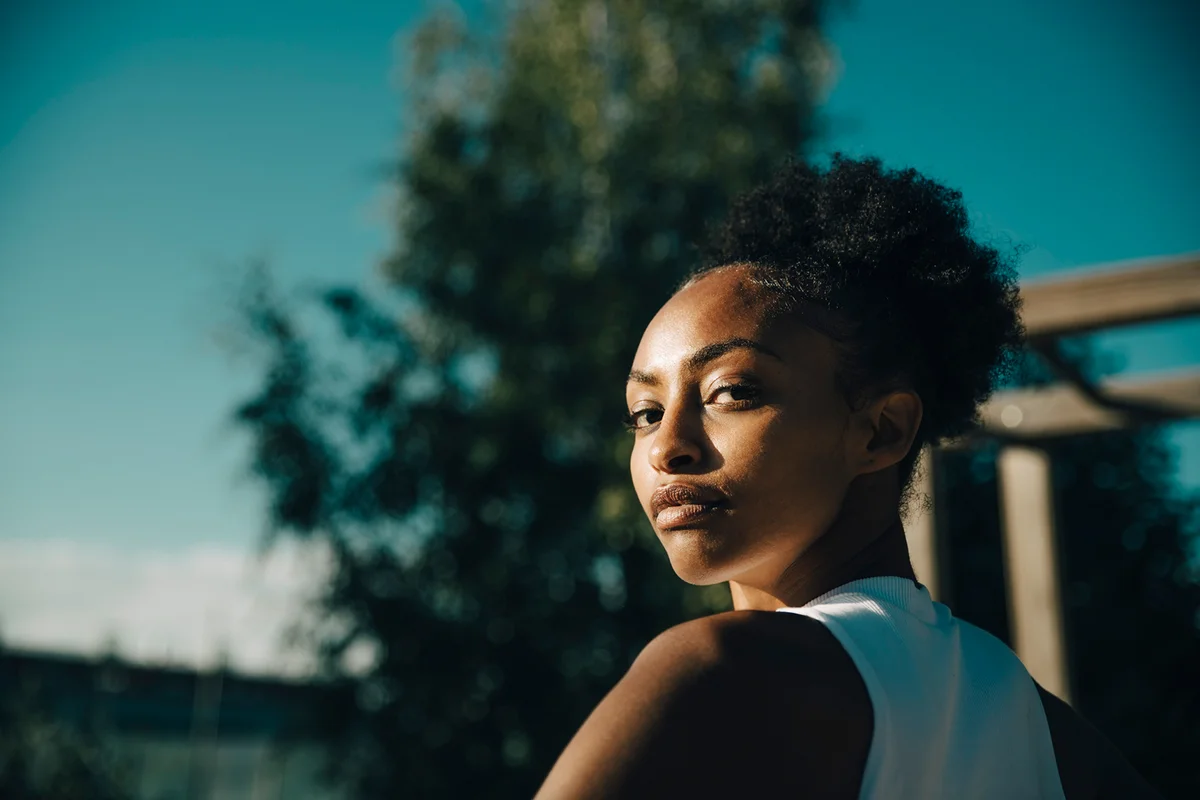 Portrait of female athlete looking over shoulder on sunny day