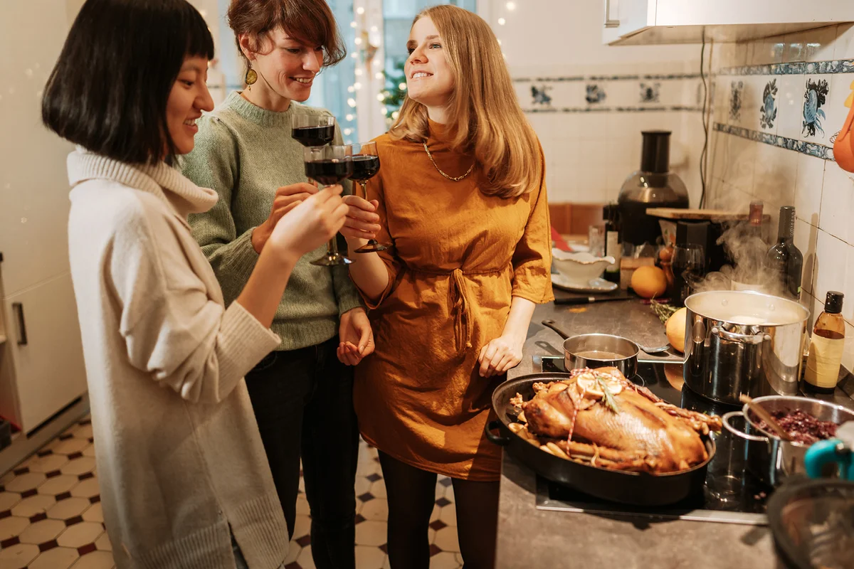 Friends preparing thanksgiving meal together and drinking wine