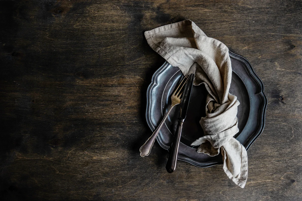 Overhead view of a black cutlery set on a black plate and black table
