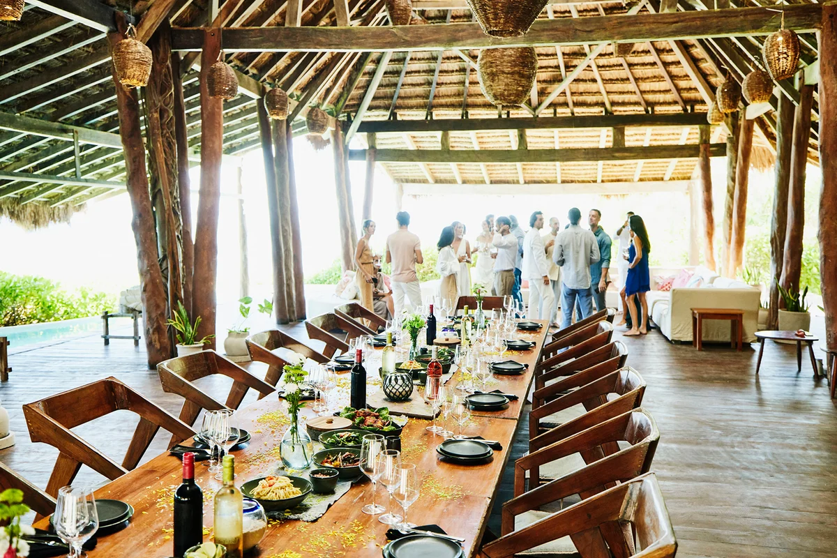 Wide shot of long table set for wedding reception dinner in outdoor pavilion at tropical luxury villa