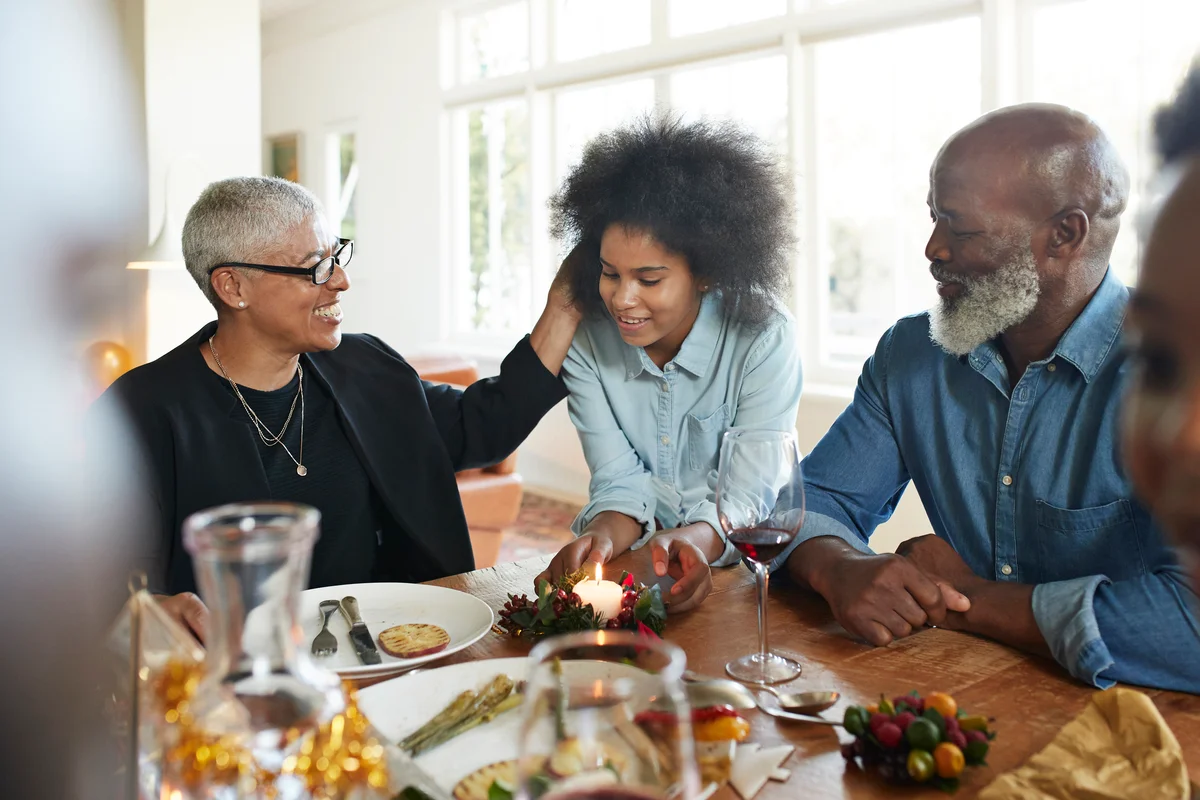 Teenage girl talking with family at dining table