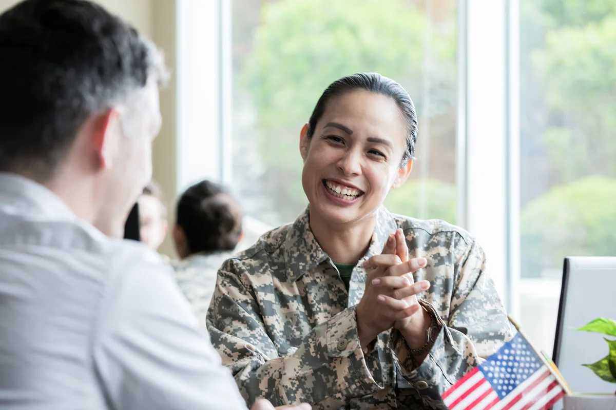 Female military recruiter smiling while discussing options with another soldier.