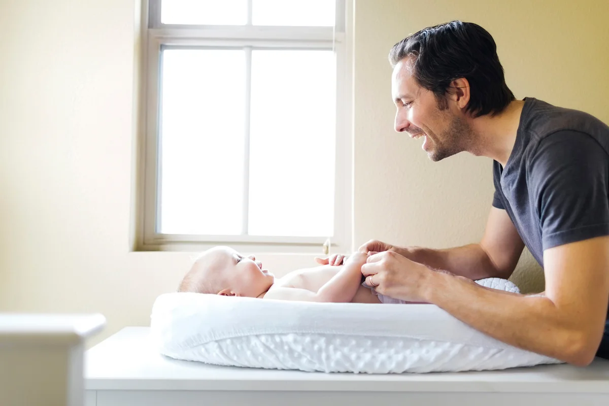 Father playing with baby boy on changing mat