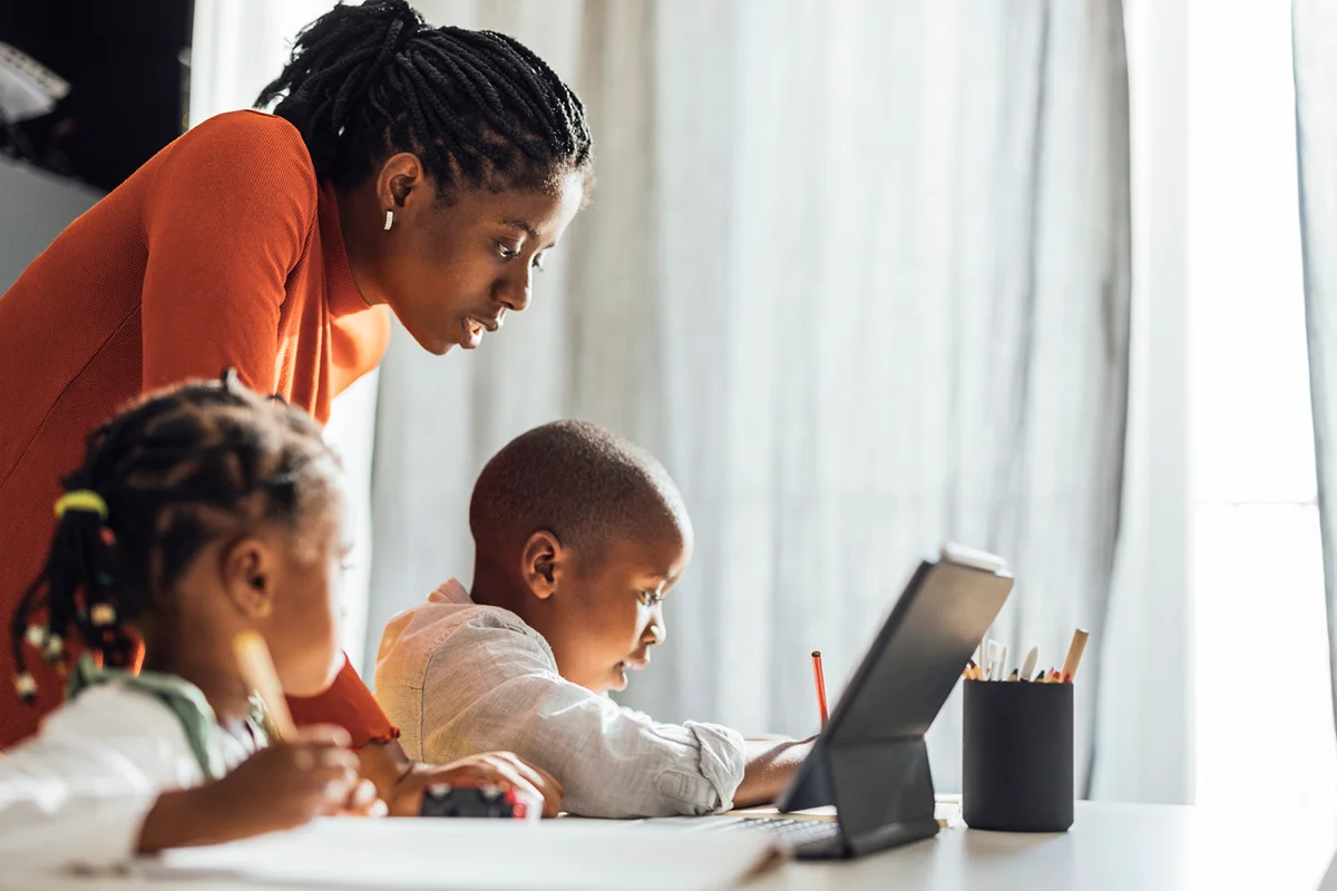 Serious Mother Helps her Children To Do Their Homework in a Living Room