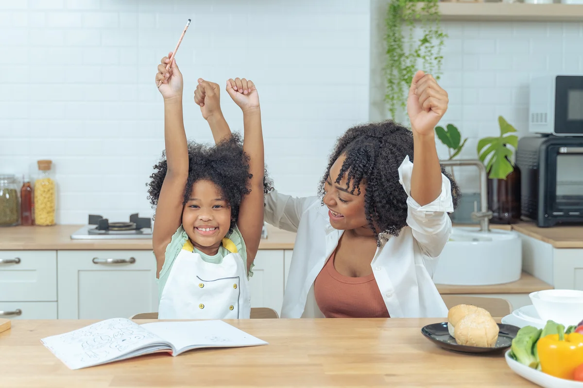 Happiness Mother helping daughter with homework at kitchen
