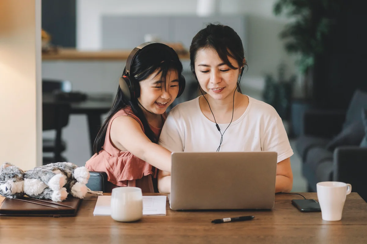mother and daughter using laptop browsing the internet at living room