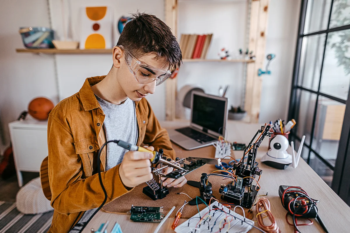 Teenage boy soldering elements on circuit board